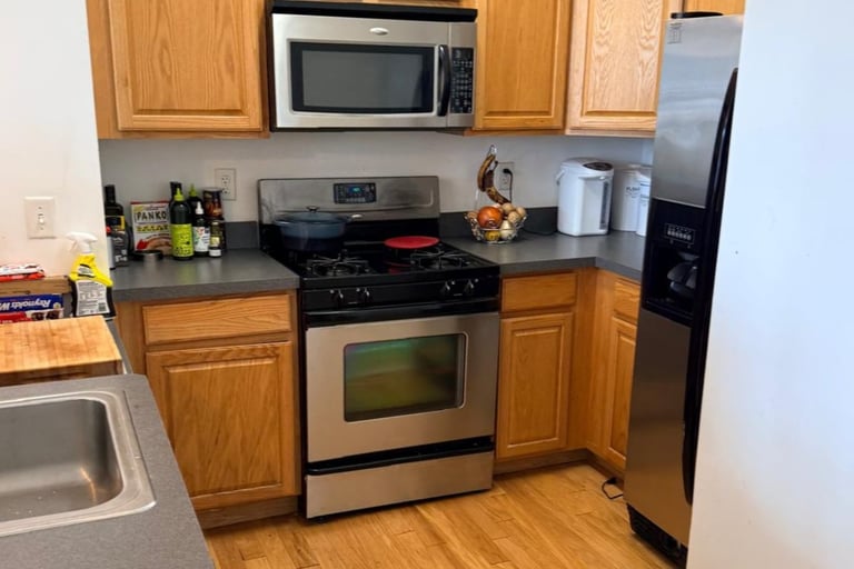 Modern kitchen with stainless steel stove and microwave, wooden cabinets, and countertop appliances